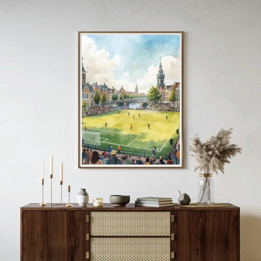Delft voetbal schilderij in donkere lijst aan witte muur boven donker houten dressoir met vaas en boeken – sportieve wall art woonkamer