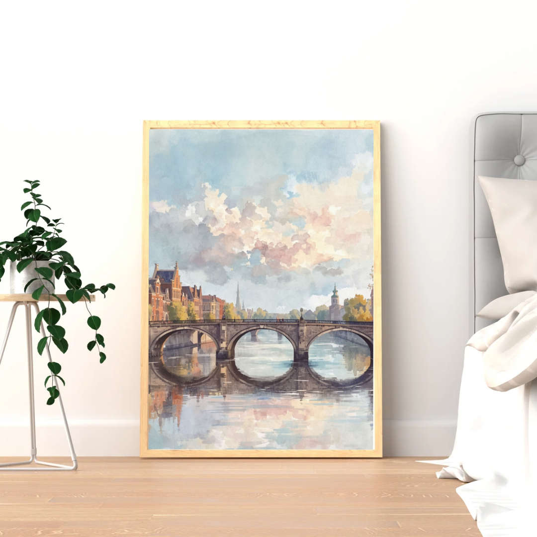 Herfstbrug schilderij in zwarte lijst staand op lichte houten vloer tegen witte muur naast grote groene plant – aquarel wall art woonkamer