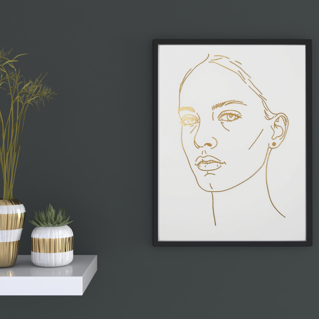 Gouden vrouwengezicht line art canvas schilderij met open blik in zwarte lijst aan donkergrijze muur in hal met decoratieve vaas en kaarsen — elegante wanddecoratie