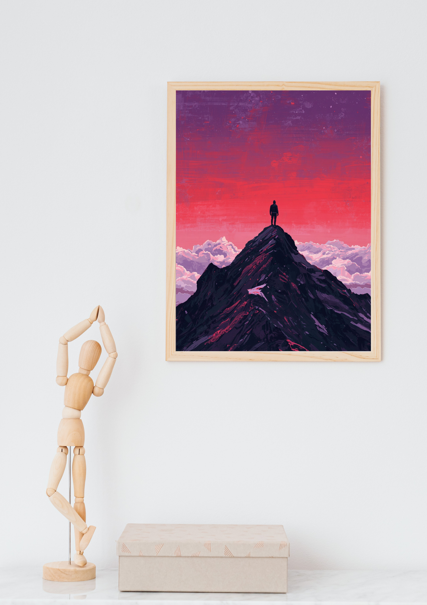 Bergpiek silhouet magenta schilderij in naturel houten lijst aan witte muur naast houten paspop en beige doos – digitaal wall art thuiskantoor