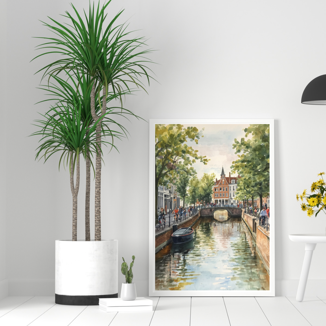 Amsterdam zomergracht schilderij in donkere lijst aan witte muur naast grote groene palm in witte pot op lichte vloer – aquarel wall art woonkamer

