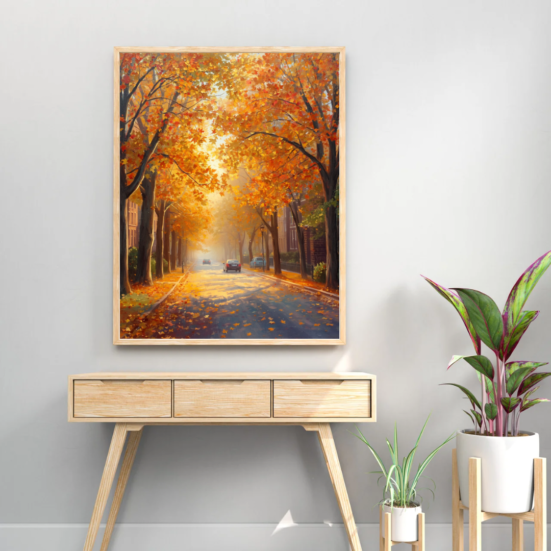 Deventer herfst bomentunnel schilderij in zwarte lijst staand op licht houten sidetable met groene plant tegen witte muur – olieverf wall art woonkamer
