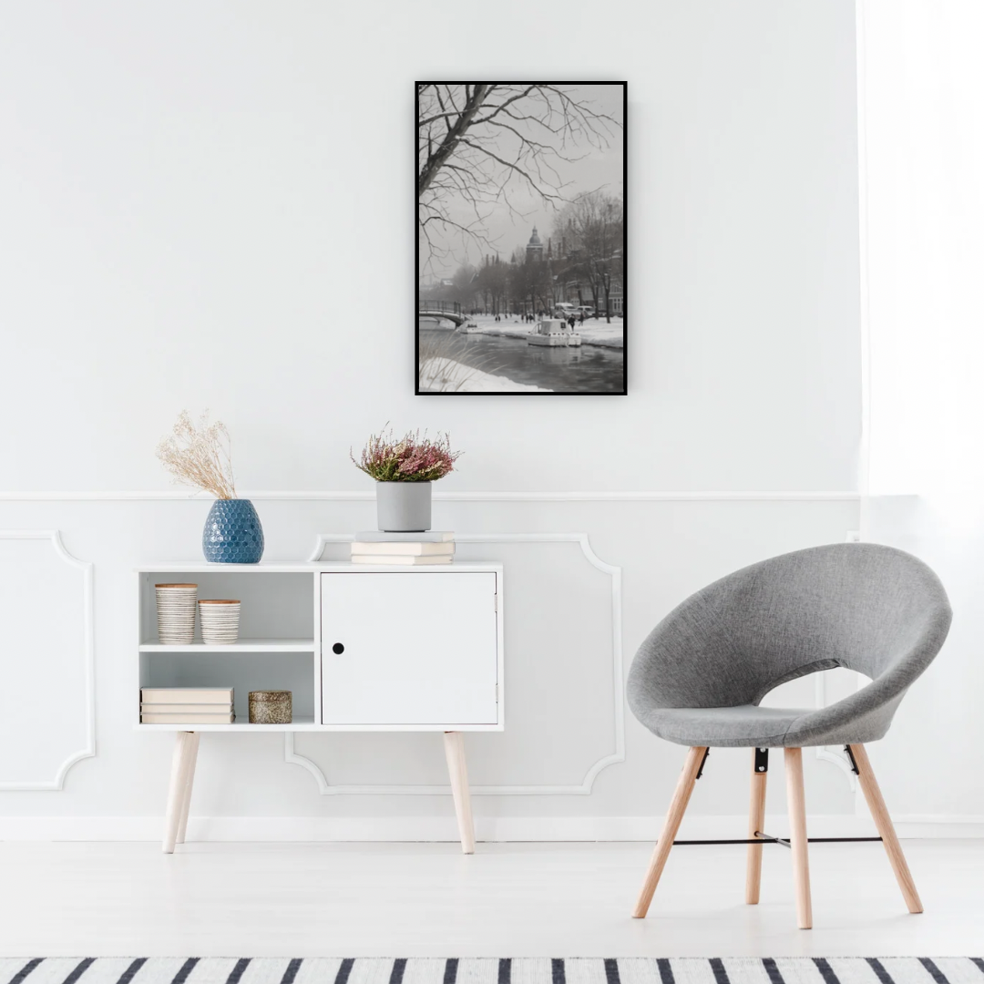 Winter natuur schilderij in zwarte lijst aan witte muur boven wit sidetable met grijze ronde stoel en witte vaas – olieverf wall art woonkamer
