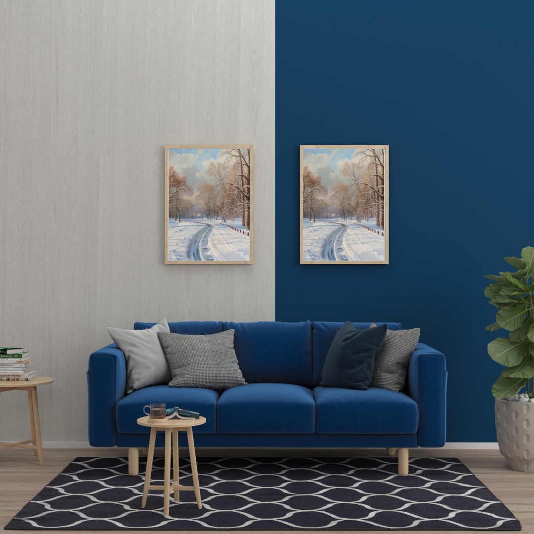 Winter verlaten sneeuwweg schilderij in witte lijst aan blauwe muur boven blauwe bank met grijze kussens en ronde bijzettafel – olieverf wall art woonkamer
