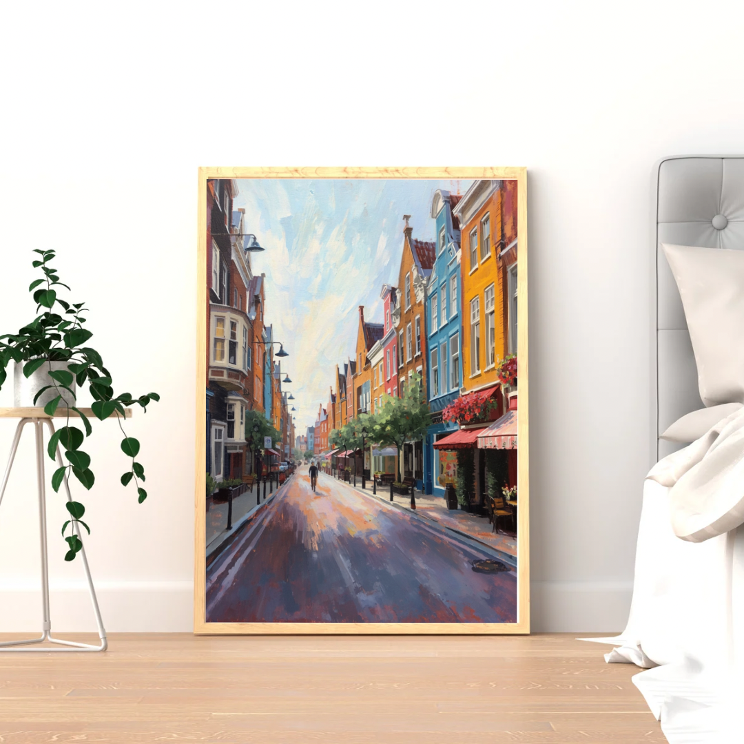 Groningen kleurrijke straat schilderij in houten lijst staand op lichte vloer naast groene plant in witte ruimte – wall art print interieur
