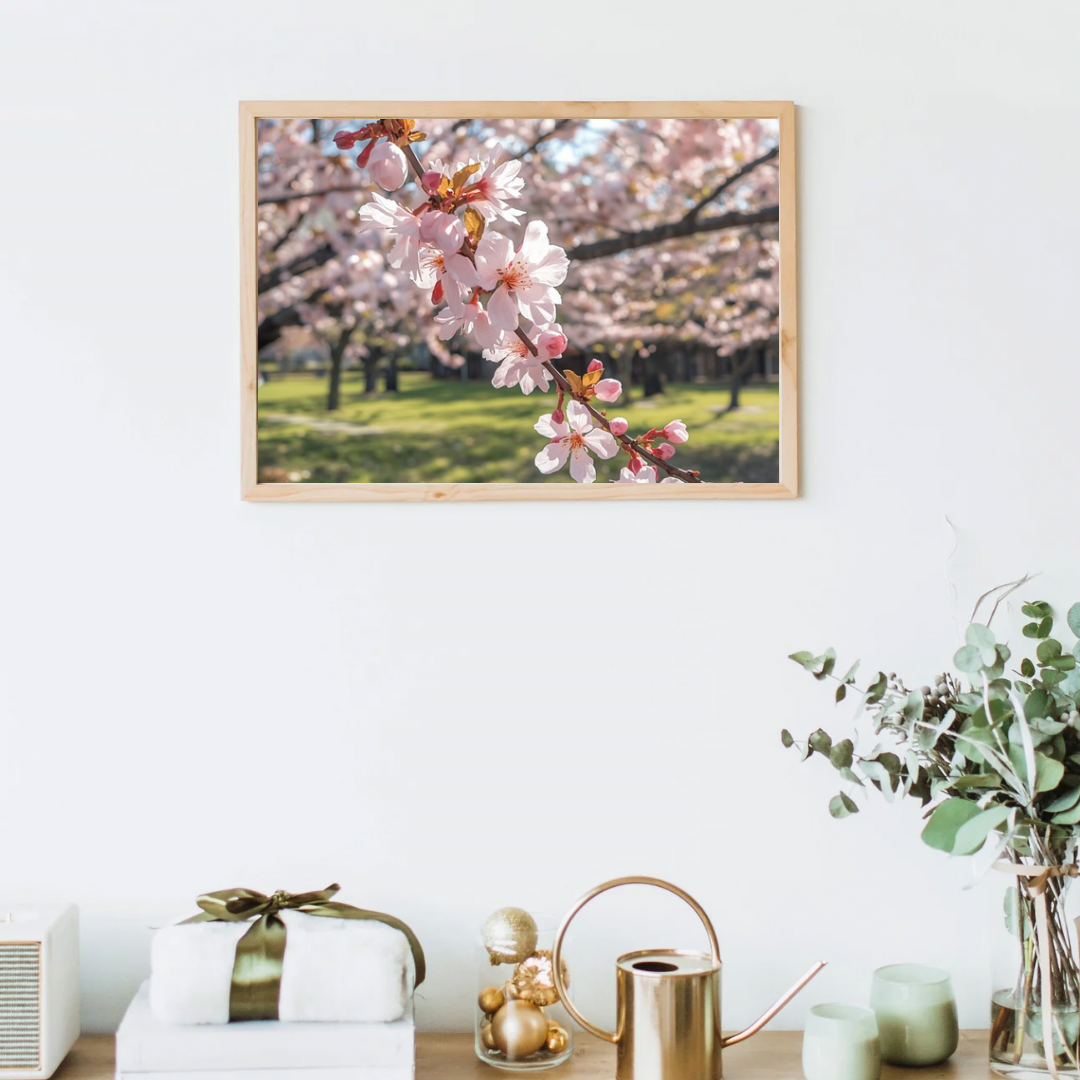 Kersenbloesem schilderij in houten lijst aan witte muur boven wit dressoir met gouden vaas en groene plant in woonkamer – bloemen wall art print

