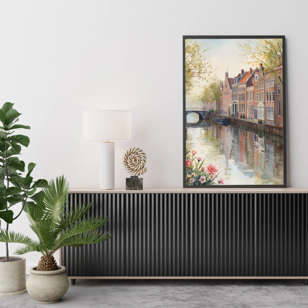 Alkmaar lente gracht schilderij in zwarte lijst aan witte muur boven zwart geribbeld dressoir met grote groene plant in woonkamer – aquarel wall art print
