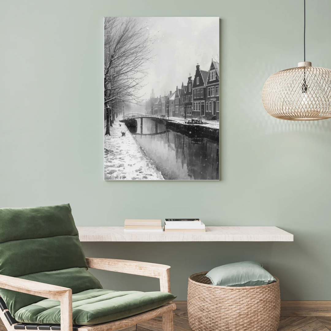 Alkmaar sneeuwval gracht schilderij als canvas aan saliegroen muur boven groene fauteuil met witte kussens en rieten mand in woonkamer – zwart-wit wall art print
