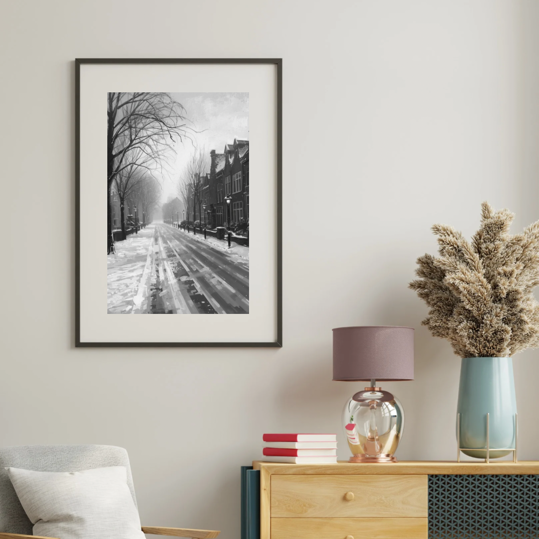 Alkmaar sneeuwstraat schilderij in zwarte lijst aan beige muur boven houten dressoir met gouden lamp, vaas en decoratieve objecten – zwart-wit wall art print woonkamer
