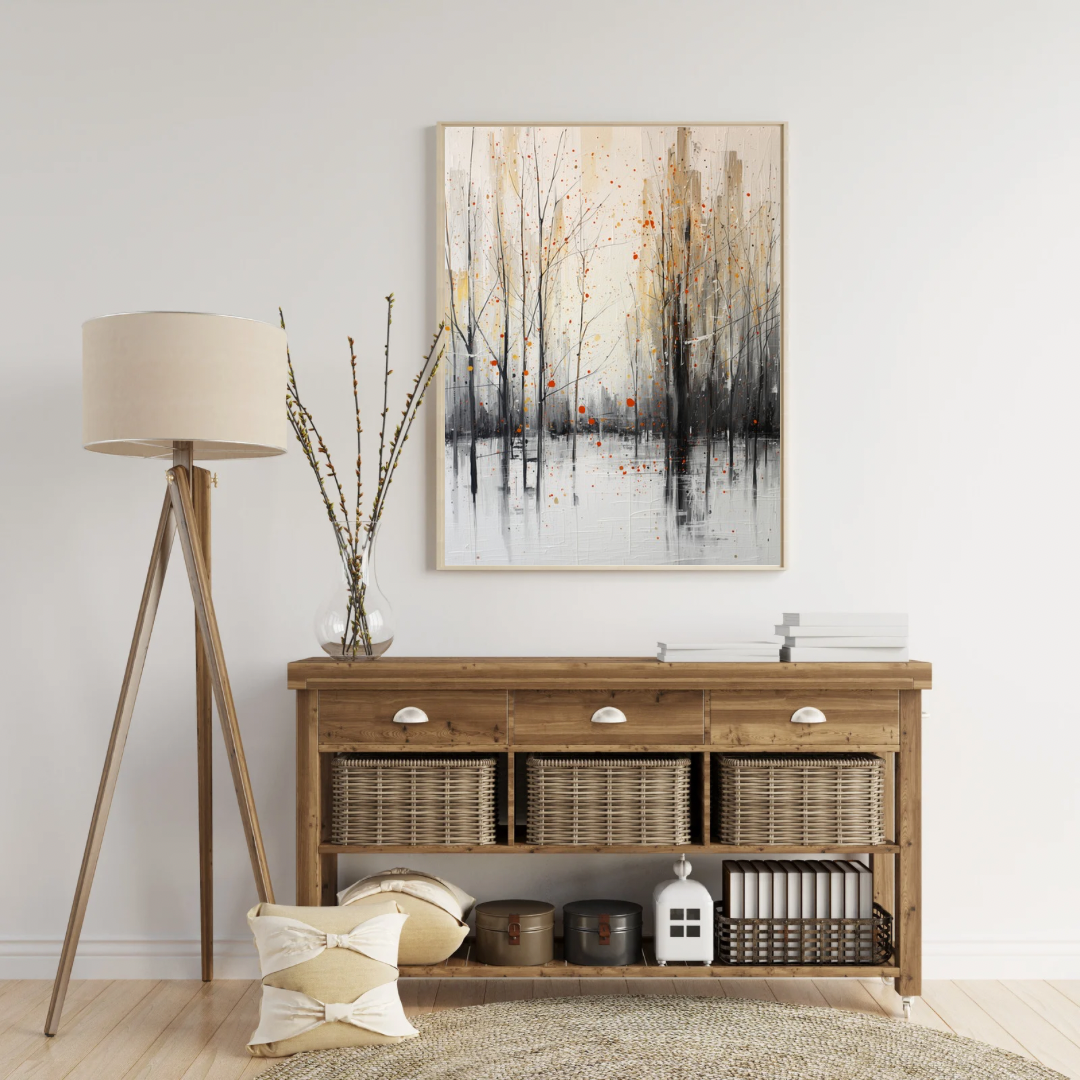 Abstract winterbomen verfspetters schilderij in houten lijst aan witte muur naast houten vloerlamp en rieten dressoir met decoratieve objecten – wall art print woonkamer
