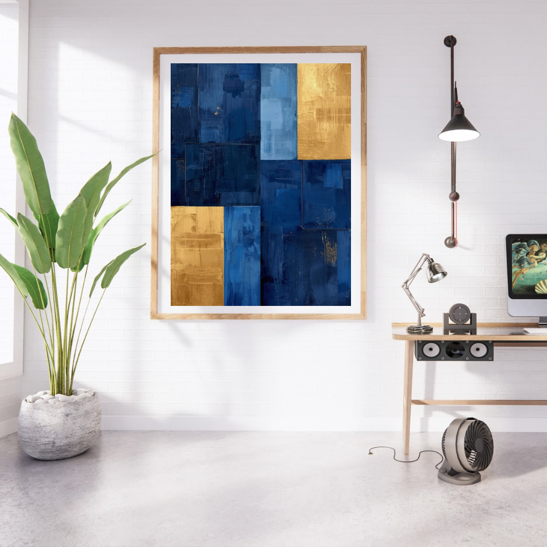 Abstract blokken marineblauw goud schilderij in naturel houten lijst aan witte muur naast grote groene plant en houten bureau met lamp – abstract olieverf wall art studeerkamer
