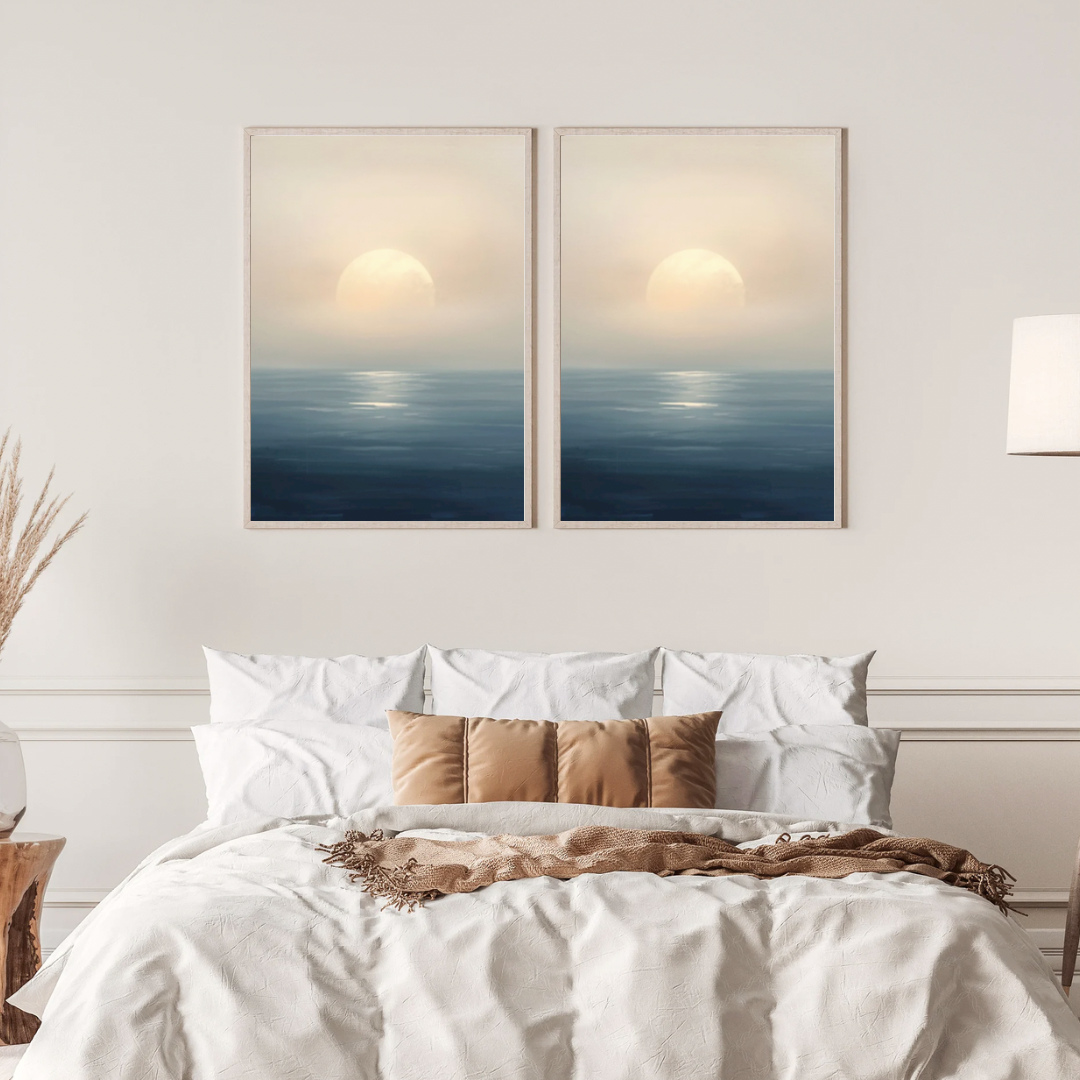Abstract zonsondergang zee schilderij met gouden zon en mistige horizon in twee gouden lijsten naast elkaar aan witte muur boven bed met linnen beddengoed – sereen wall art slaapkamer
