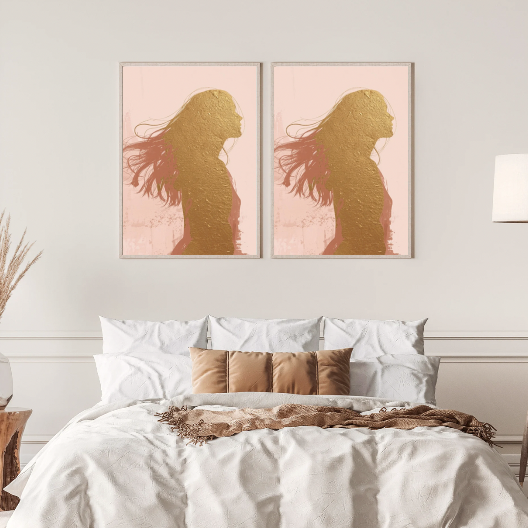 Vrouw silhouet schilderij met wapperende haren in roze gloed in twee gouden lijsten naast elkaar aan witte muur boven bed met linnen beddengoed – vrouwelijk wall art slaapkamer
