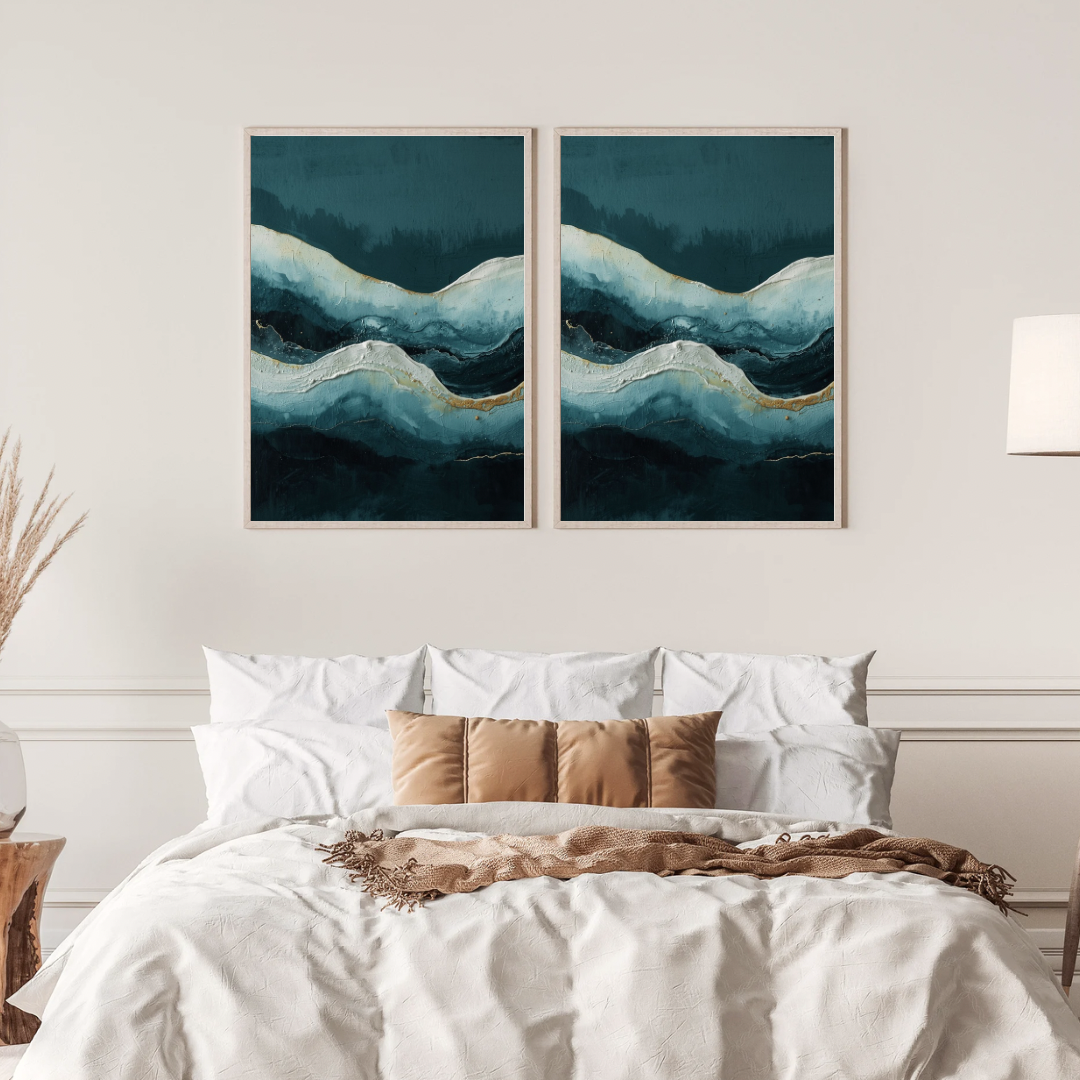 Abstract oceaan golf schilderij met diepblauwe golven en gouden lichtlijn in twee gouden lijsten naast elkaar aan witte muur boven bed met linnen beddengoed – maritiem wall art slaapkamer
