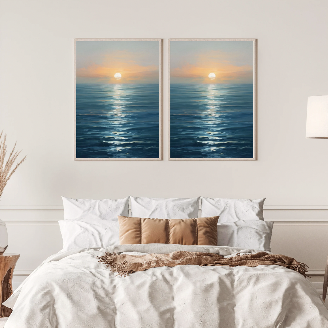 Zonsondergang zee schilderij met gouden zon en spiegelend blauw water in twee gouden lijsten naast elkaar aan witte muur boven bed met linnen beddengoed – cinematisch wall art slaapkamer
