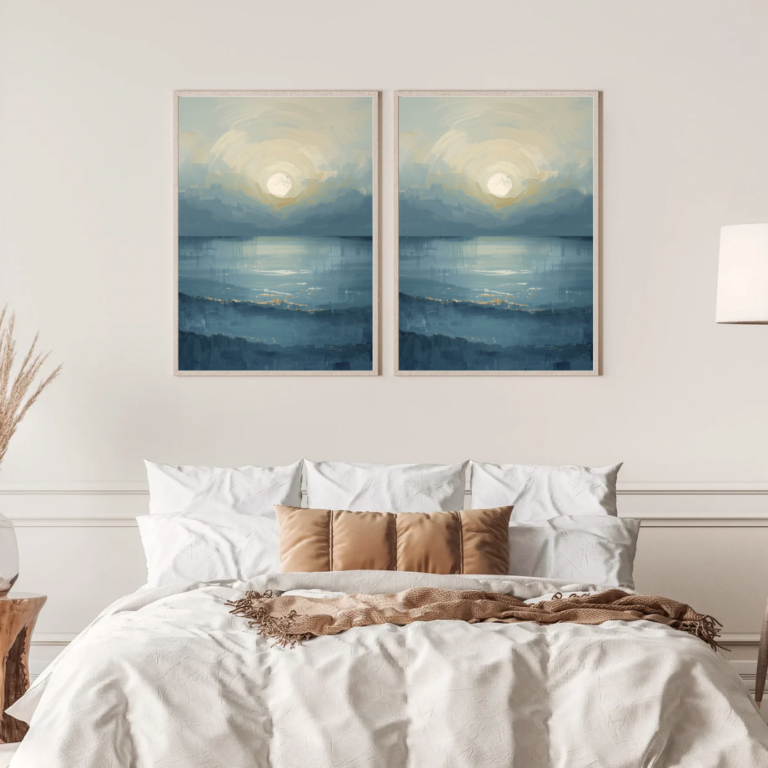 Abstract maanlicht zee schilderij met zachte maan en mistige blauwe horizon in twee gouden lijsten naast elkaar aan witte muur boven bed met linnen beddengoed – sereen wall art slaapkamer
