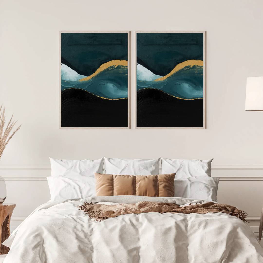 Abstract teal zwart goud schilderij met gouden golf en donkere vlakken in twee gouden lijsten naast elkaar aan witte muur boven bed met linnen beddengoed – dramatisch wall art slaapkamer
