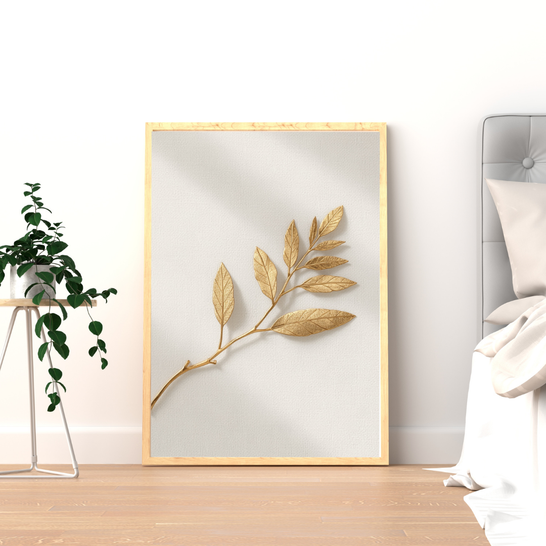 Droge gouden tak schilderij met warme goudbeige bladtak en schaduwspel in gouden lijst staand op houten vloer naast groene plant – naturel wall art logeerkamer
