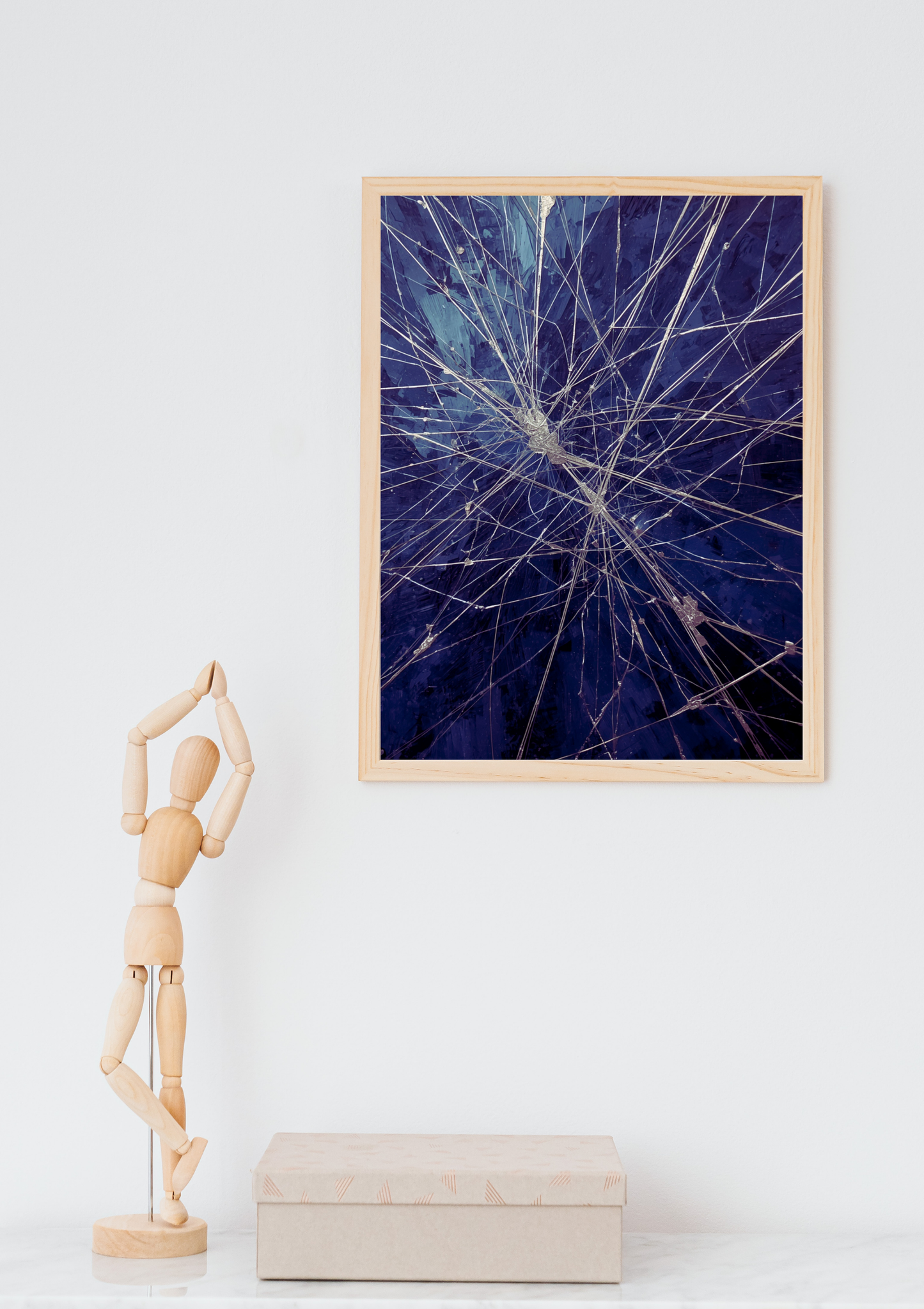 Abstract neuraal explosie schilderij in naturel houten lijst aan witte muur naast houten paspop en beige doos – abstract wall art thuiskantoor
