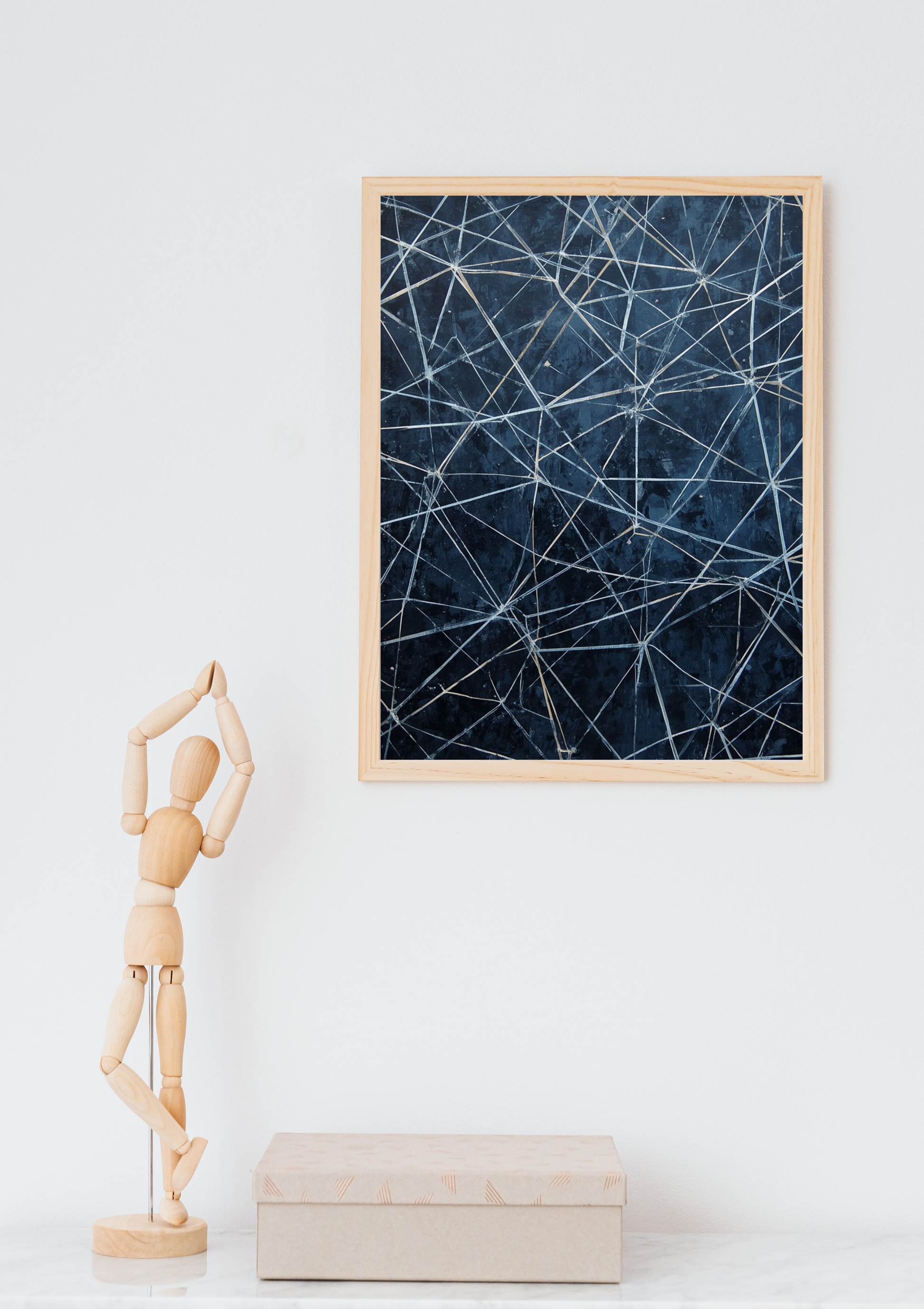 Abstract lijnennetwerk marineblauw schilderij in naturel houten lijst aan witte muur naast houten paspop en beige doos – abstract olieverf wall art thuiskantoor
