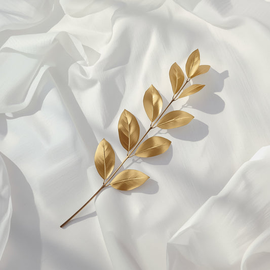 Botanisch schilderij met warme goudbeige bladtak met ovale blaadjes liggend op zijdezacht wit satijnen fond met subtiele plooien – luxueus sereen wall art print voor de logeerkamer
